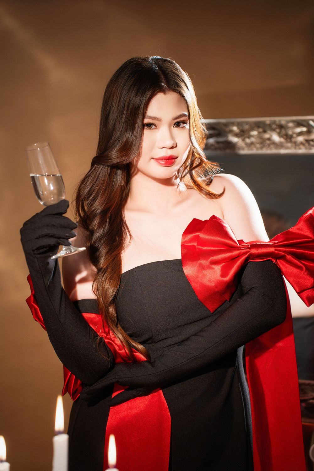 Glamorous studio birthday portrait of a woman in an elegant black and red dress with candlelight, by an Auckland photographer.