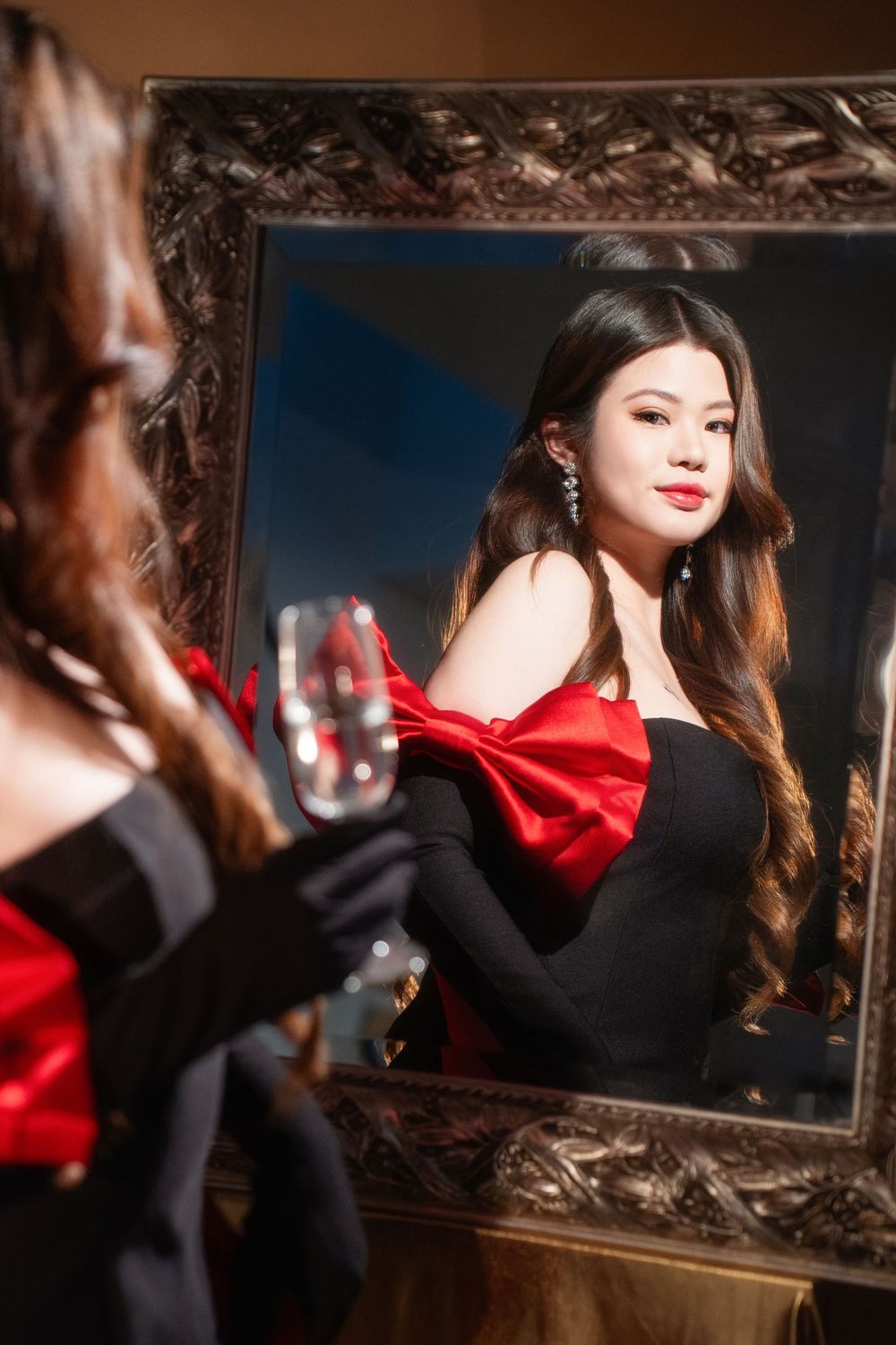 Glamorous studio birthday portrait of a woman in an elegant black and red dress with candlelight, by an Auckland photographer.