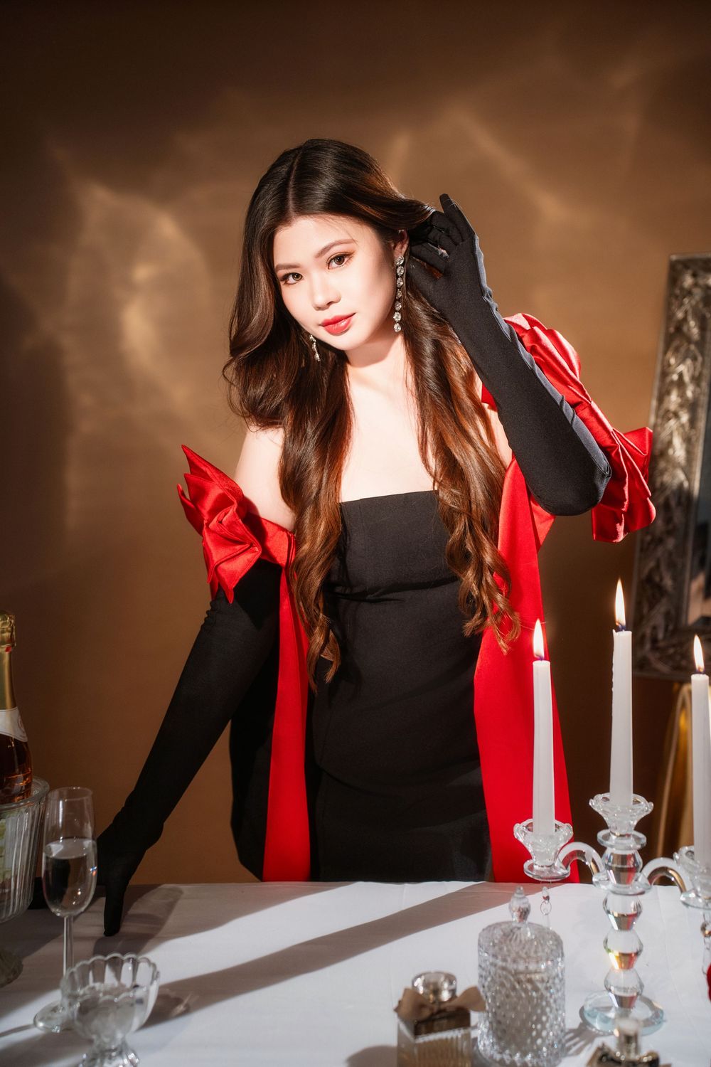 Glamorous studio birthday portrait of a woman in an elegant black and red dress with candlelight, by an Auckland photographer.