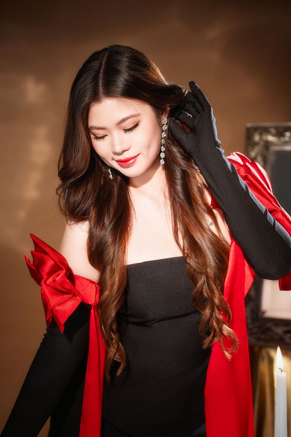 Glamorous studio birthday portrait of a woman in an elegant black and red dress with candlelight, by an Auckland photographer.