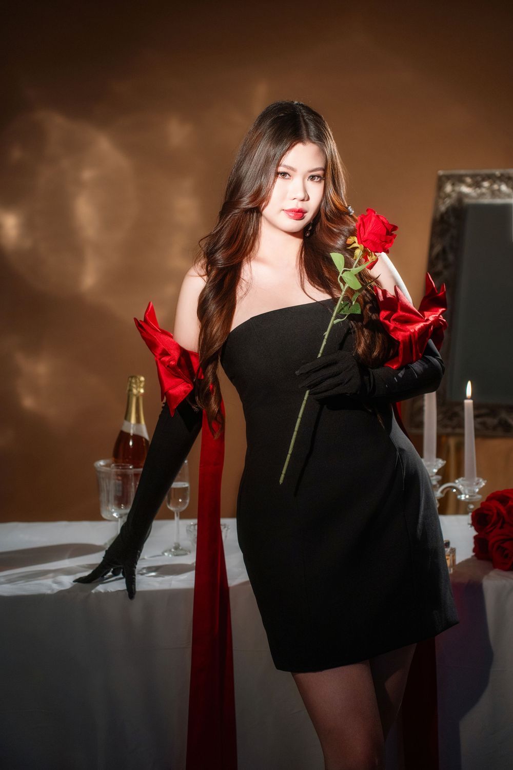 Glamorous studio birthday portrait of a woman in an elegant black and red dress with candlelight, by an Auckland photographer.