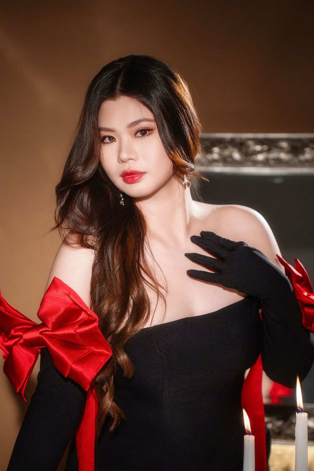 Glamorous studio birthday portrait of a woman in an elegant black and red dress with candlelight, by an Auckland photographer.