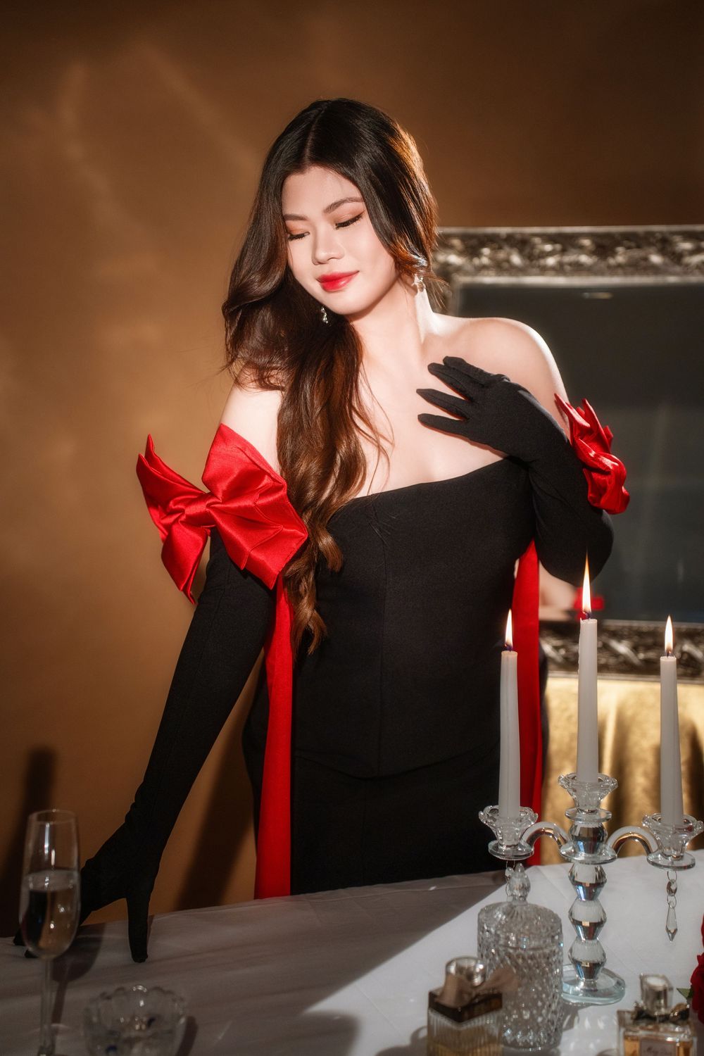Glamorous studio birthday portrait of a woman in an elegant black and red dress with candlelight, by an Auckland photographer.