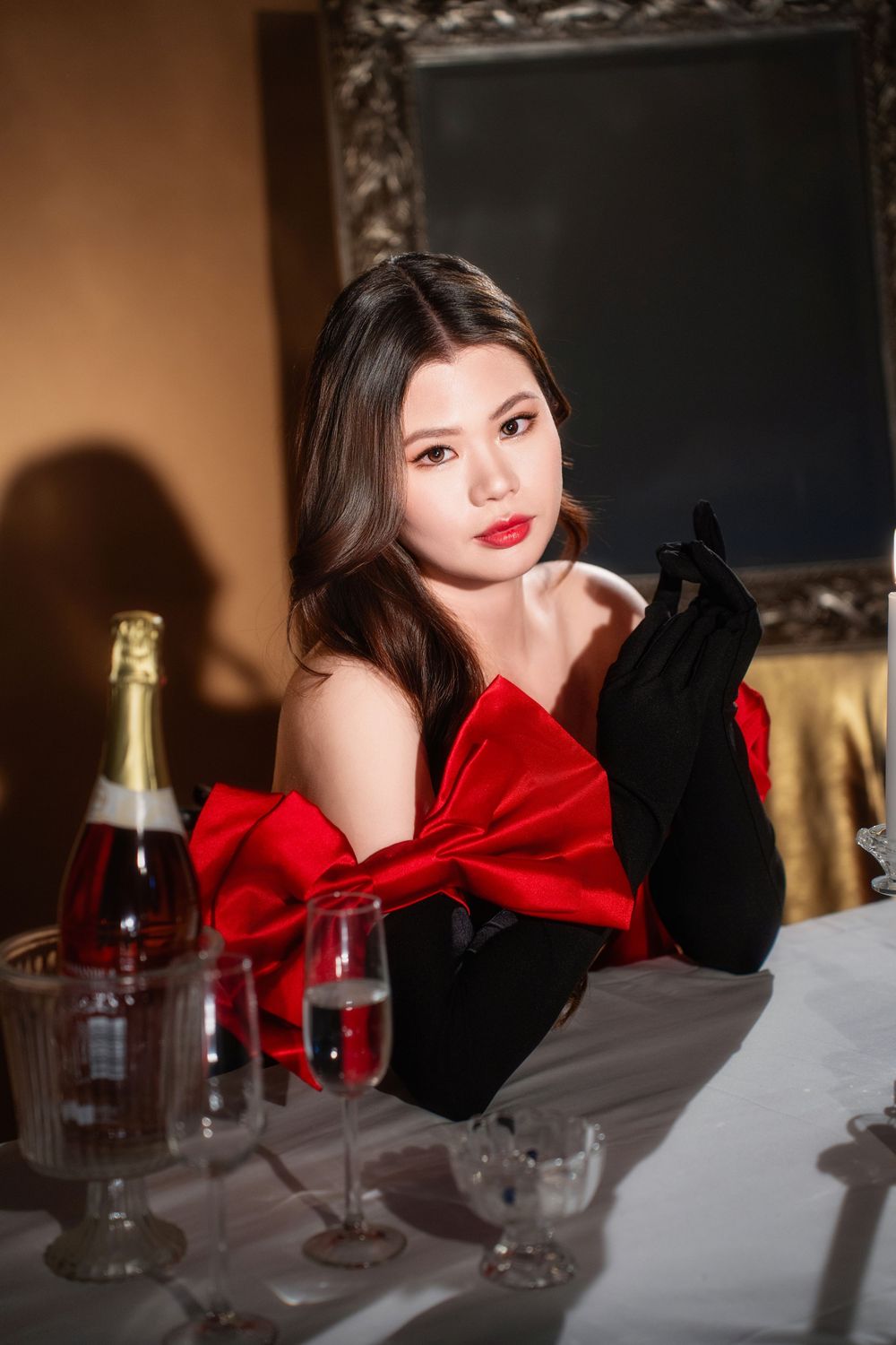 Glamorous studio birthday portrait of a woman in an elegant black and red dress with candlelight, by an Auckland photographer.