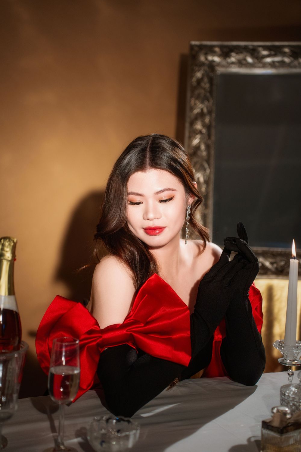 Glamorous studio birthday portrait of a woman in an elegant black and red dress with candlelight, by an Auckland photographer.