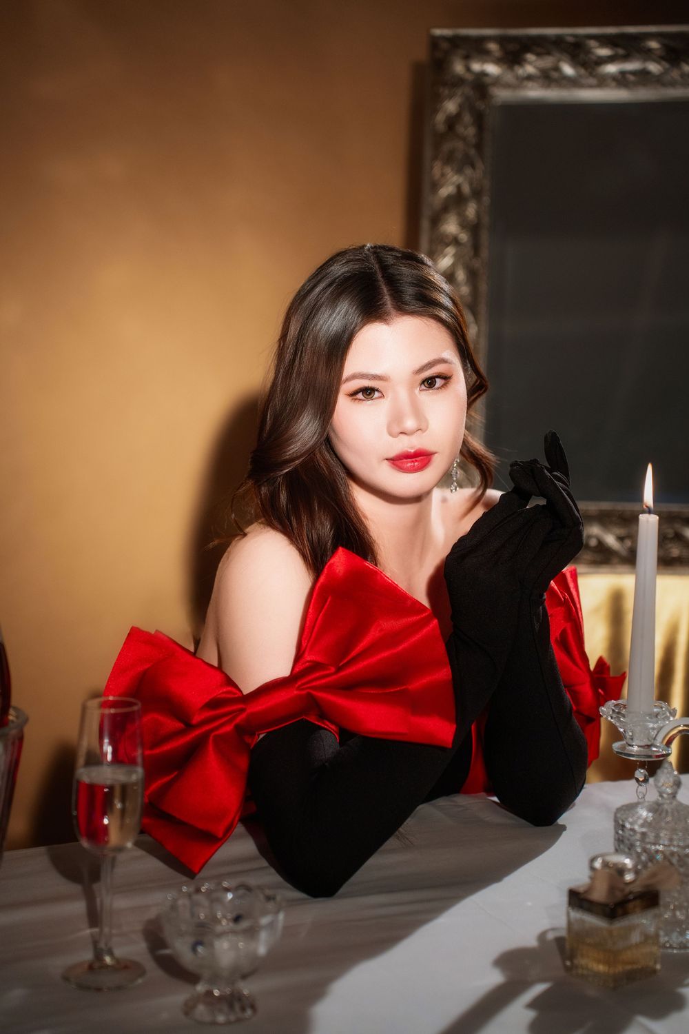 Glamorous studio birthday portrait of a woman in an elegant black and red dress with candlelight, by an Auckland photographer.