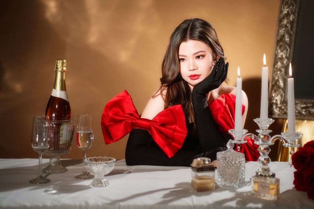 Glamorous studio birthday portrait of a woman in an elegant black and red dress with candlelight, by an Auckland photographer.