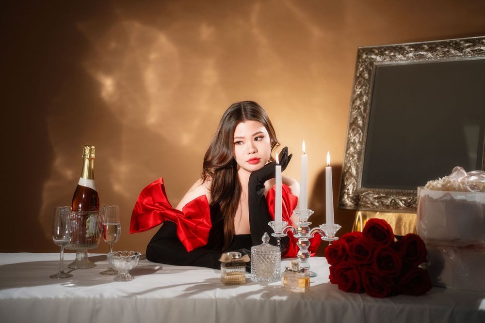Glamorous studio birthday portrait of a woman in an elegant black and red dress with candlelight, by an Auckland photographer.