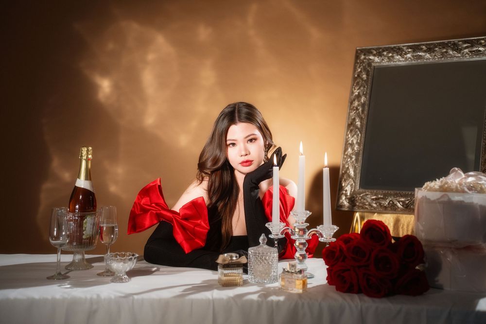 Glamorous studio birthday portrait of a woman in an elegant black and red dress with candlelight, by an Auckland photographer.