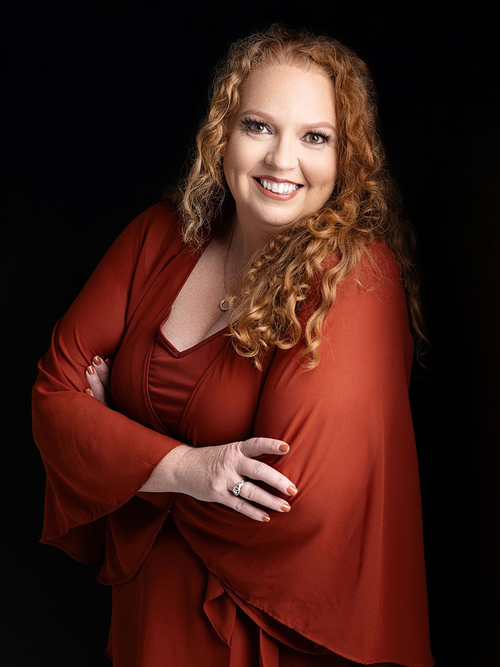 Atlanta professional studio headshot and branding photography of a confident middle-aged woman with curly red hair wearing a deep red dress.