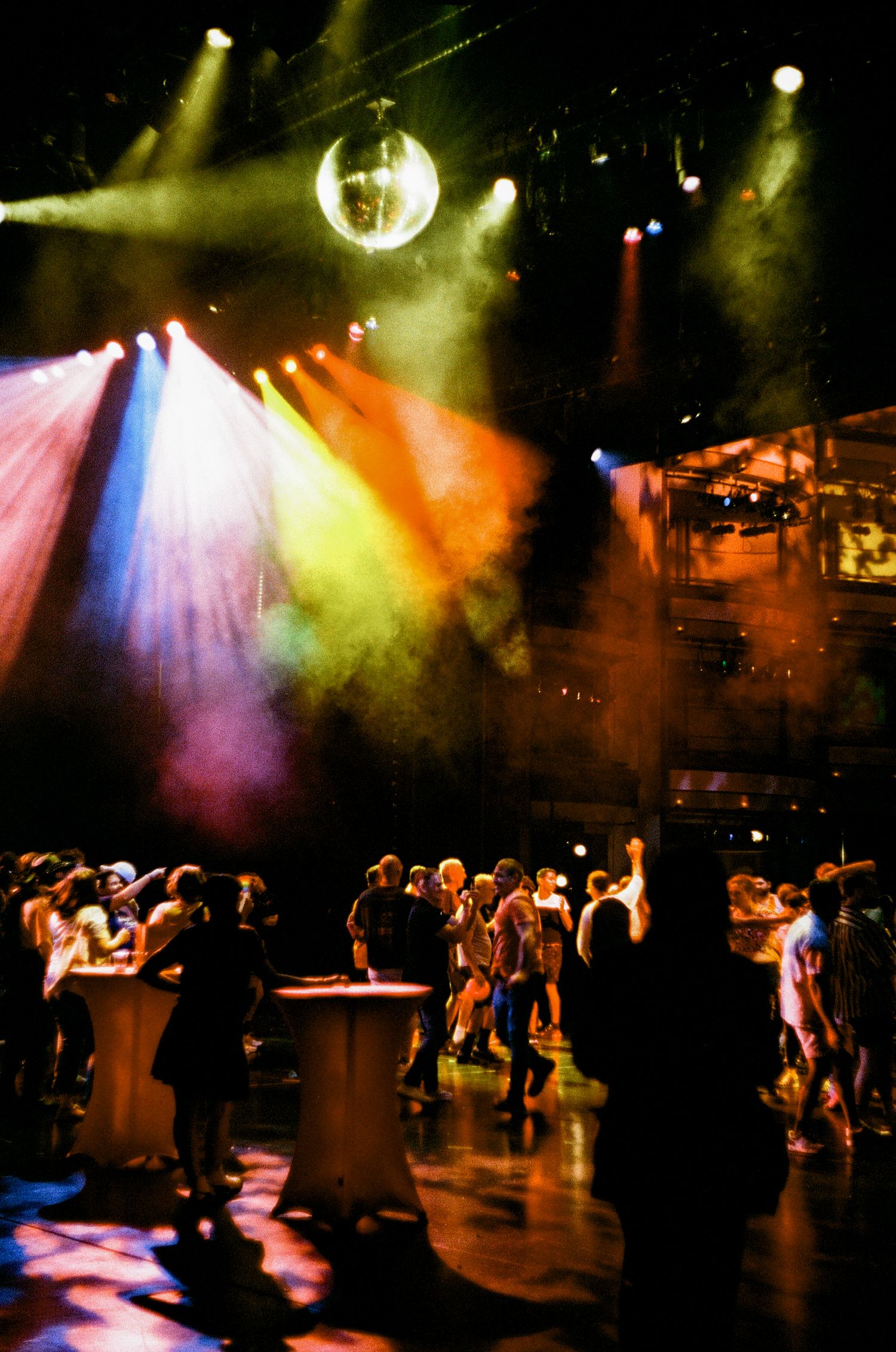 Silhouetted crowd dancing under dramatic starburst lighting effects at a nightclub or concert venue.