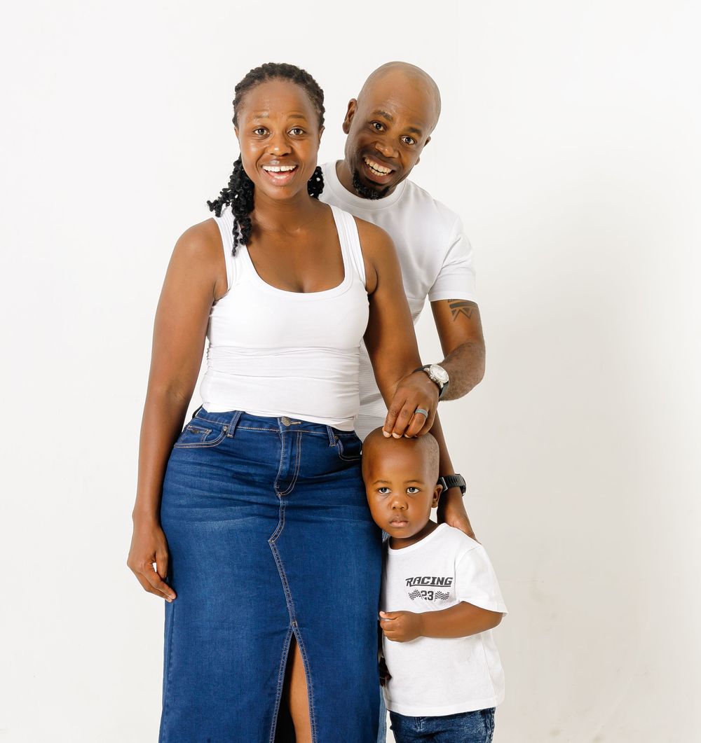 A family group wearing coordinated blue jeans and white tops poses together against a light backdrop.