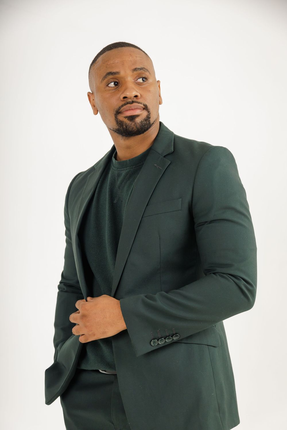 Professional studio portrait of someone wearing a dark green business suit against a white background.