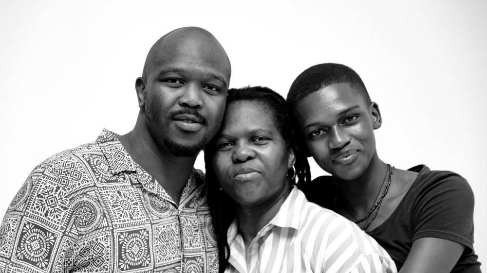 Three people pose together for a black and white portrait with one wearing a patterned shirt.