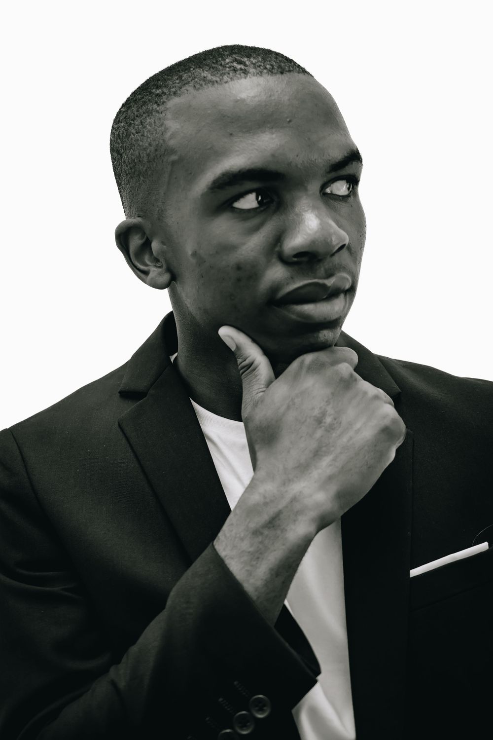 Professional black and white portrait of someone in a formal suit with hand thoughtfully placed under chin.