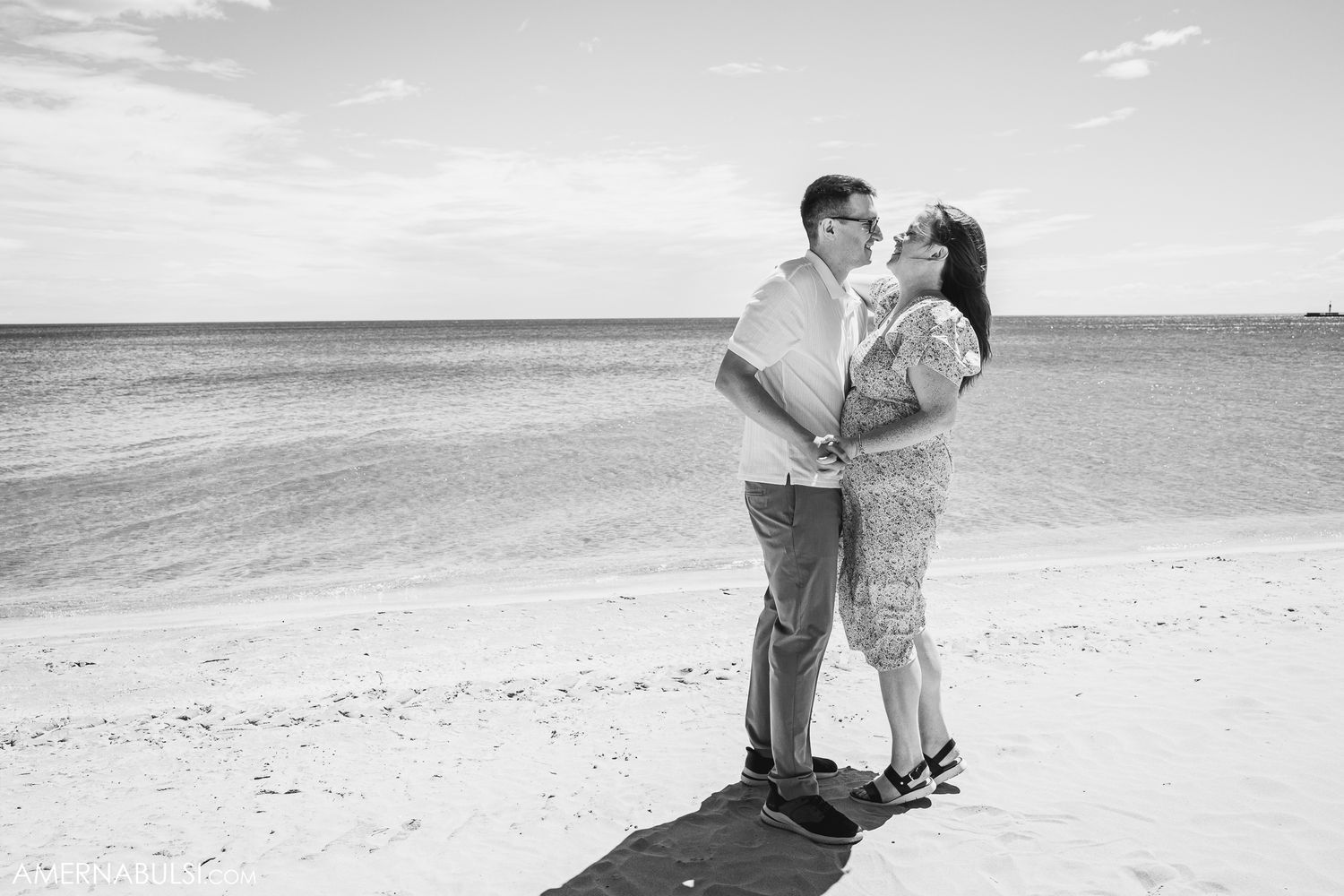 Couple sharing intimate moment on pristine sandy beach in black and white photography.