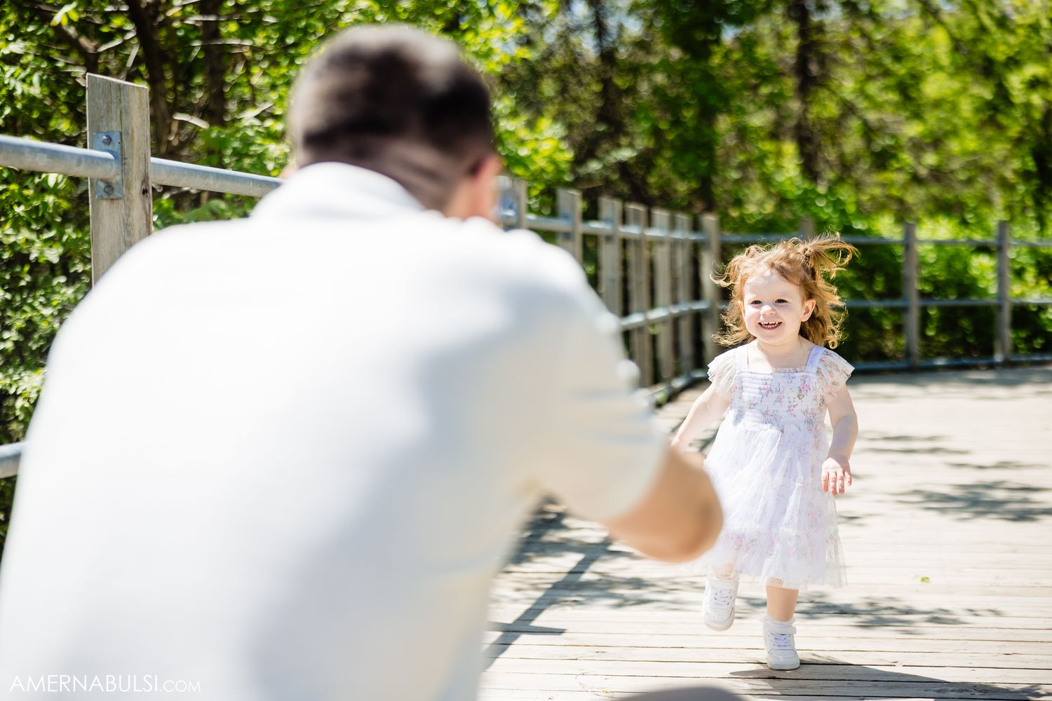 Family members dancing joyfully in blurred green garden setting with natural lighting.