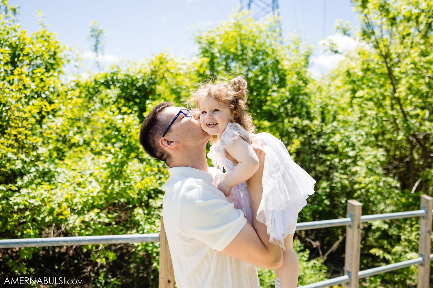 A joyful outdoor moment in a lush garden setting with sunlit greenery in the background.