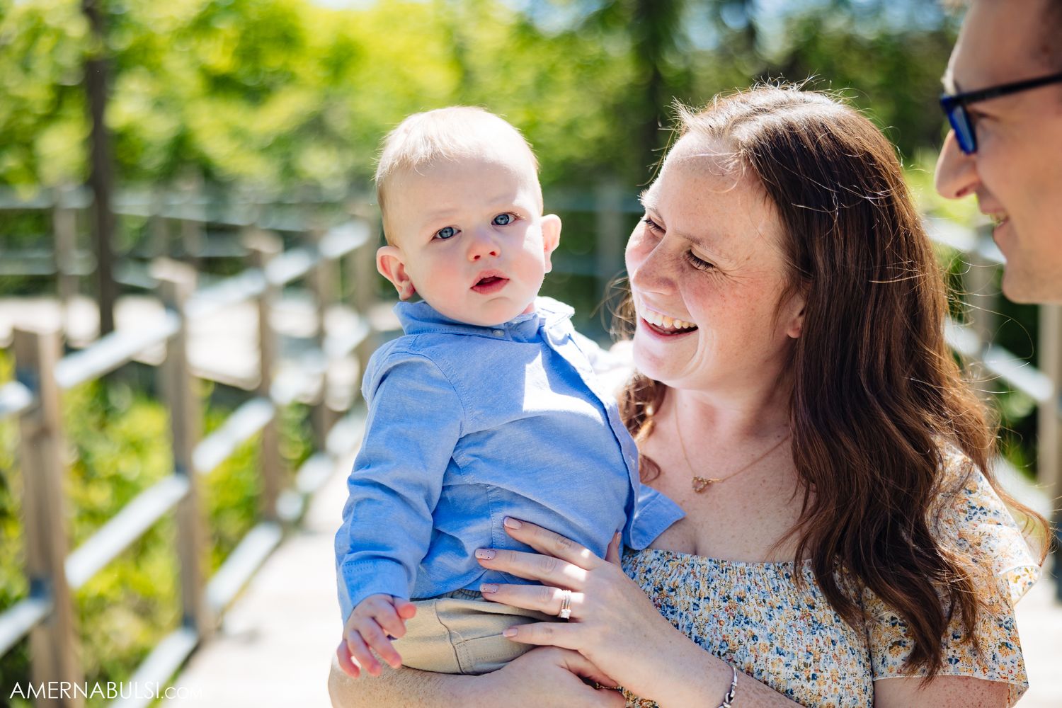 A sweet family moment captured in a lush green garden setting on a bright sunny day.