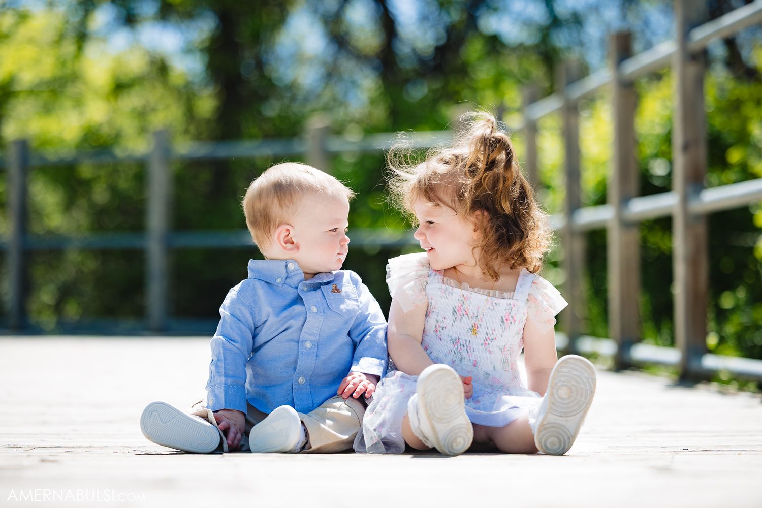 Two young children in dressy outfits sitting together on concrete steps sharing a sweet moment outdoors.