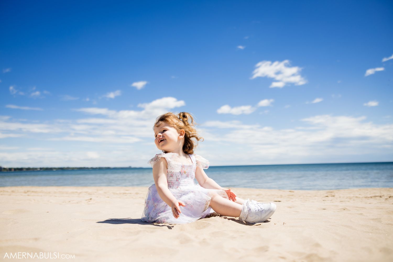 A carefree moment on a sunny beach with bright blue skies and scattered clouds overhead.