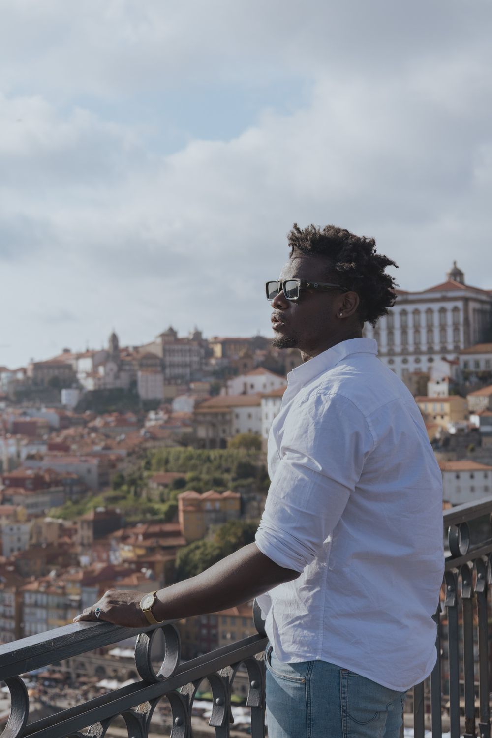 Person wearing glasses and white shirt admiring the Porto cityscape from a viewpoint.