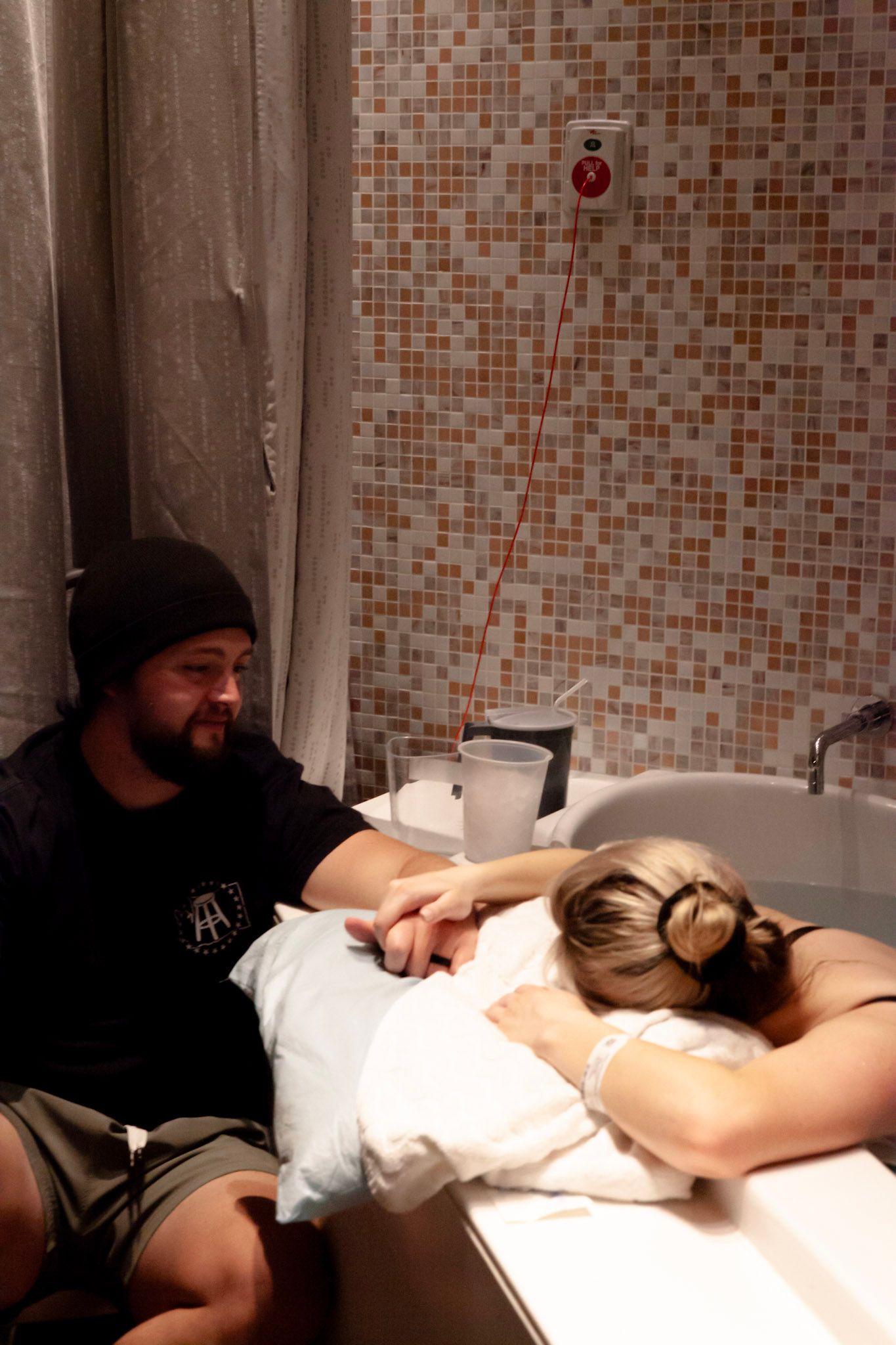 Father supporting wife through birth and labor while she soaks in a tub.
