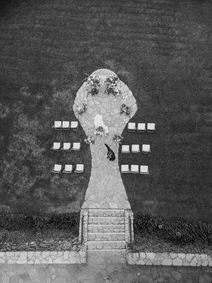 Aerial black and white view of a stone wedding ceremony setup with chairs arranged in rows leading to an elevated altar.