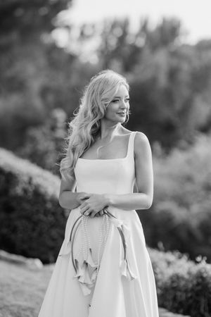 Elegant bride in sleeveless white dress poses outdoors in a romantic black and white portrait.