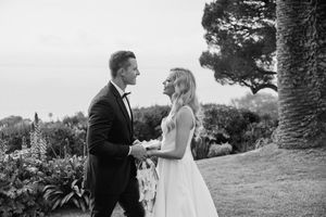 Black and white photo of a romantic wedding couple gazing at each other outdoors in a garden setting.