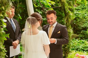 Outdoor wedding ceremony in a lush garden setting with the couple exchanging vows under natural greenery.