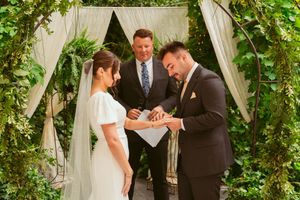 Wedding couple sharing an emotional moment during their garden ceremony under a draped arch with greenery.