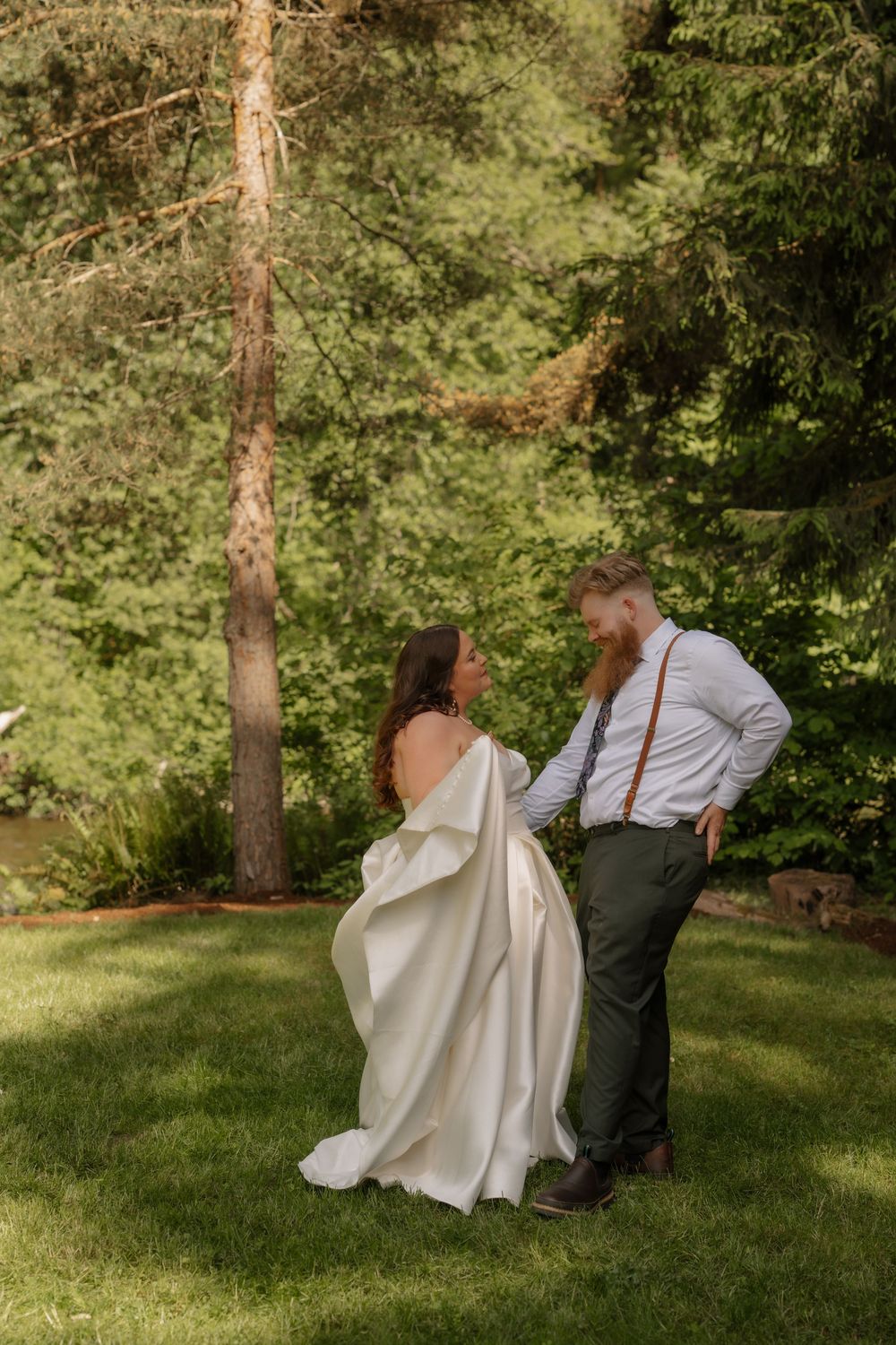 A couple shares an intimate moment outdoors in a lush garden setting during a wedding photoshoot.