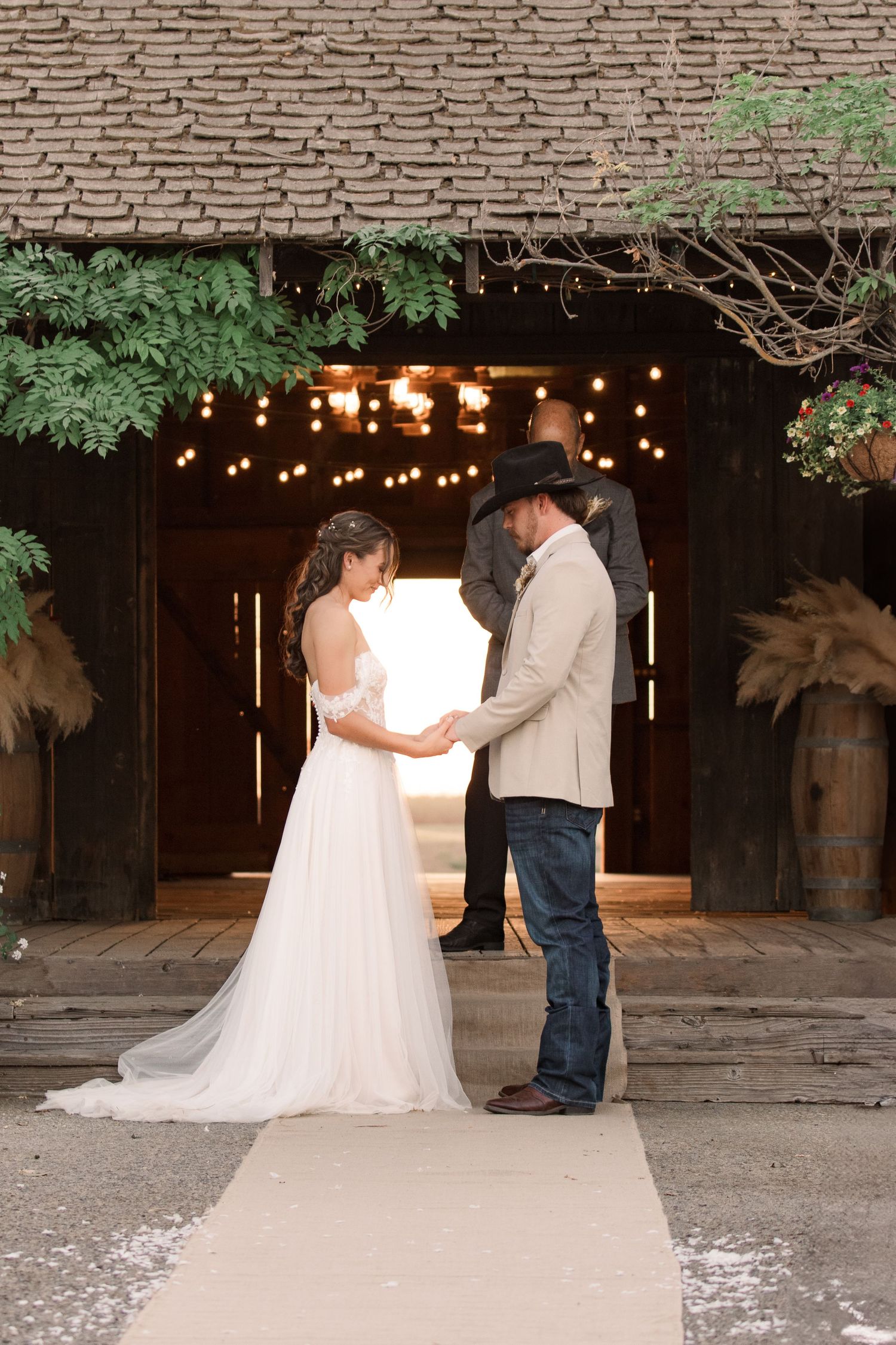 A couple shares an intimate moment under string lights at a rustic barn wedding venue.