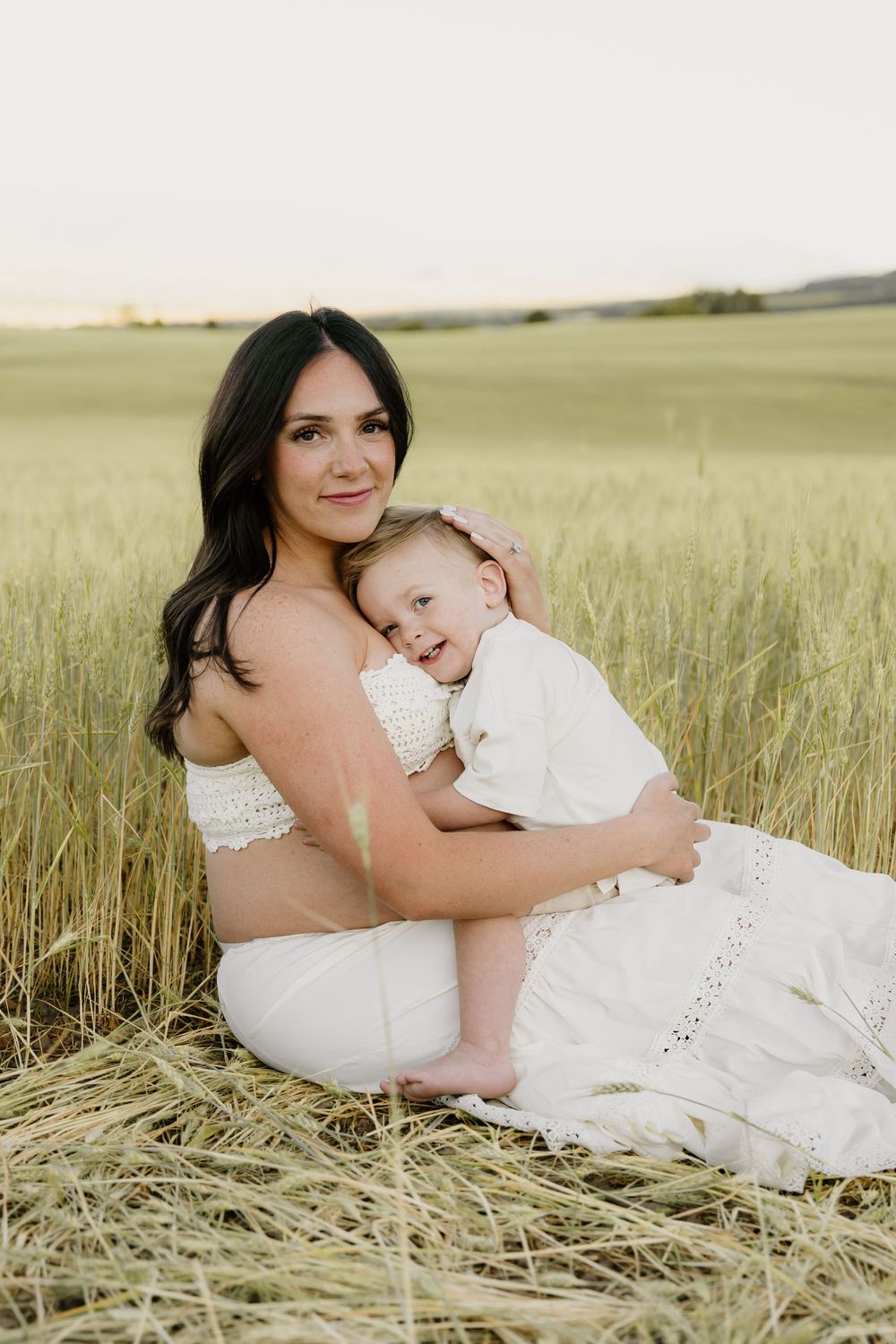 A tender moment shared between mother and child laying in a golden wheat field.