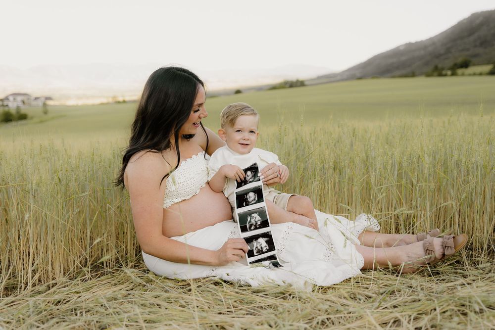 A serene family photoshoot in a golden wheat field at sunset captures tender moments between loved ones.