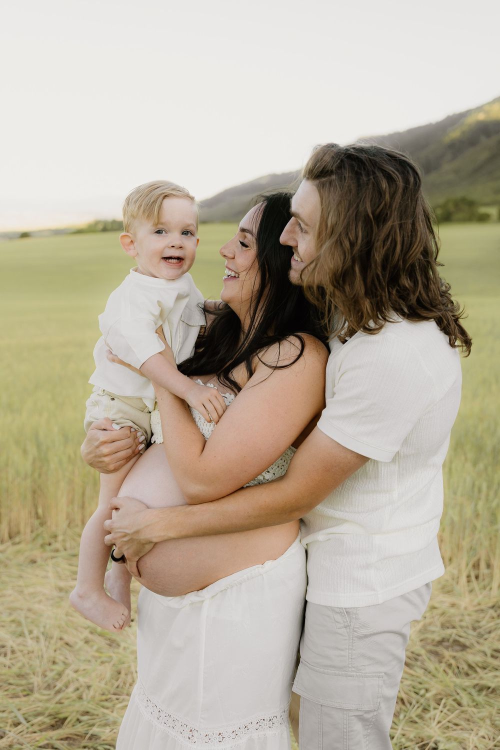 Happy family shares joyful moment together in sunny wheat field.