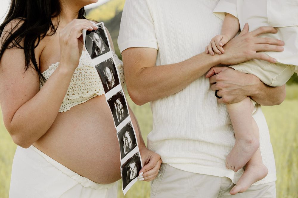 A collection of handheld ultrasound photos being displayed outdoors in a line by people wearing white.