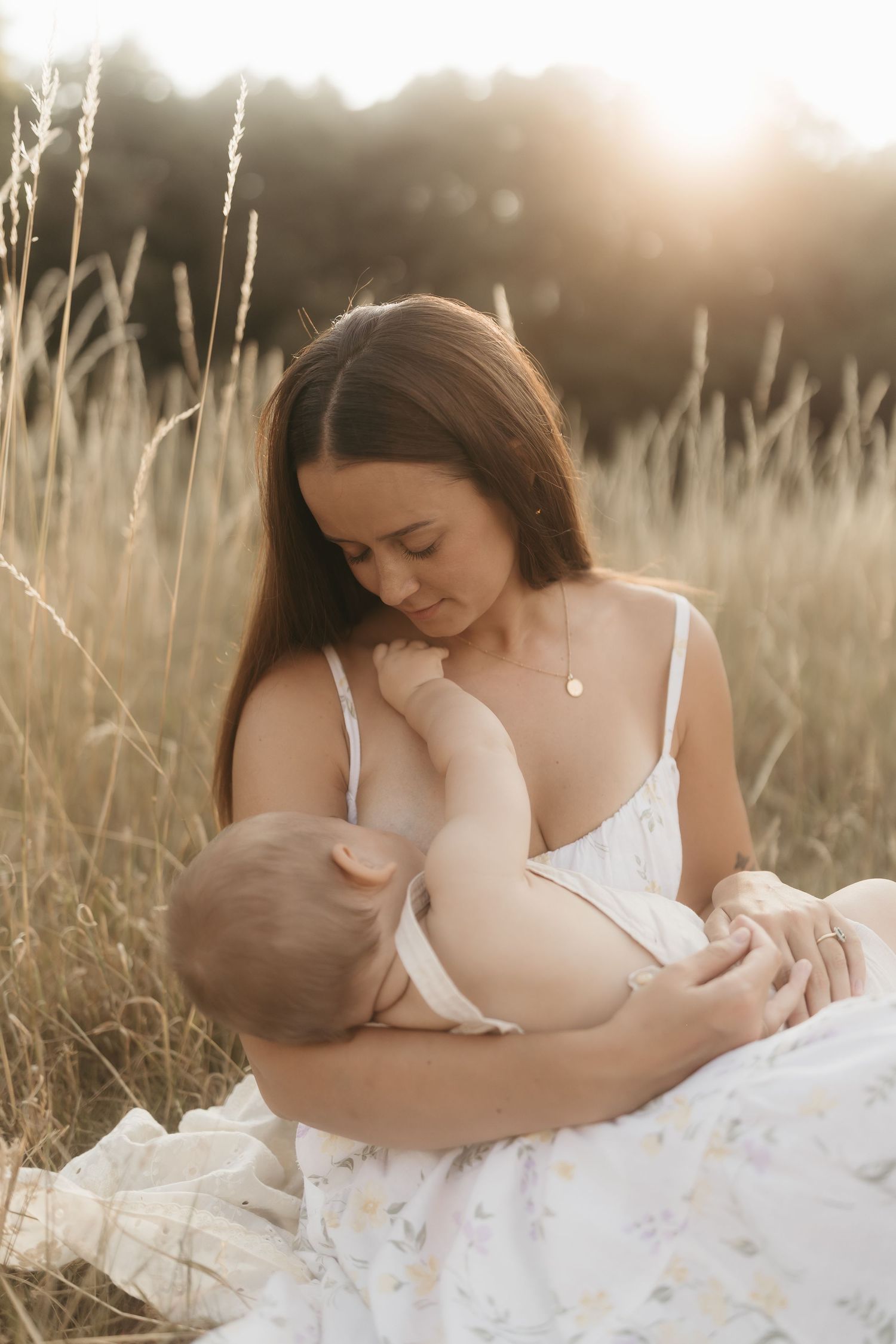 Close up of hands tenderly touching a pregnant belly draped in cream colored fabric in soft natural light.