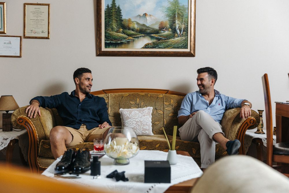 Two people having casual conversation while relaxing on a vintage brown leather couch.