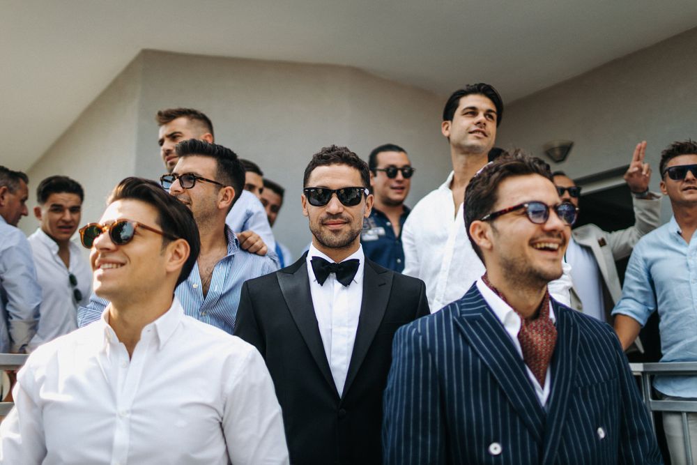 Stylishly dressed wedding party poses together outdoors.
