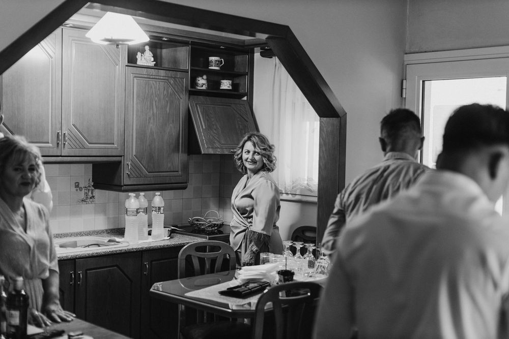 Black and white photograph of people gathering in a retro-style kitchen.