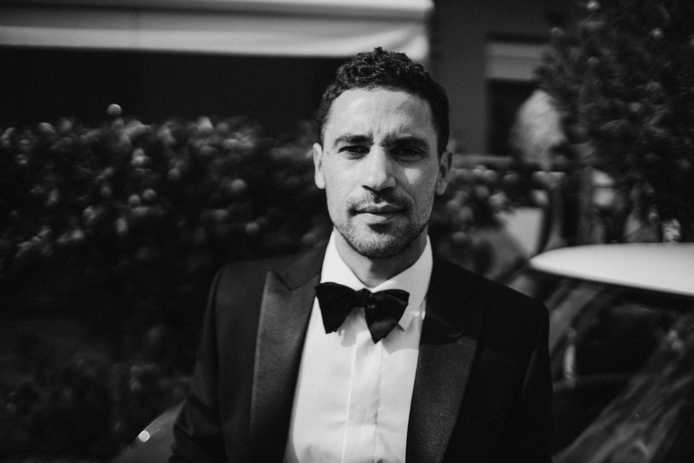 Black and white portrait of someone wearing a tuxedo with bow tie.