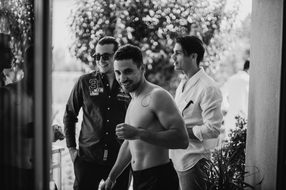 Black and white photo of three people having drinks during pre-wedding preparations.
