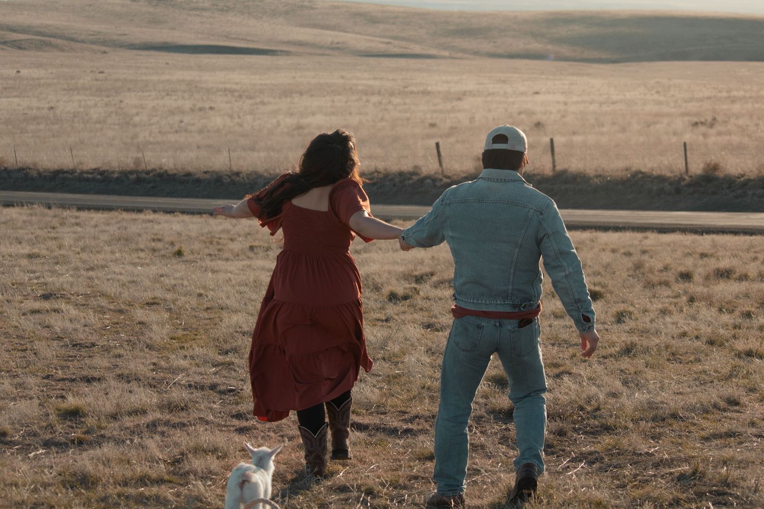 Playful photo of couple walking through an open field with their goat during sunset session in Pasco WA
