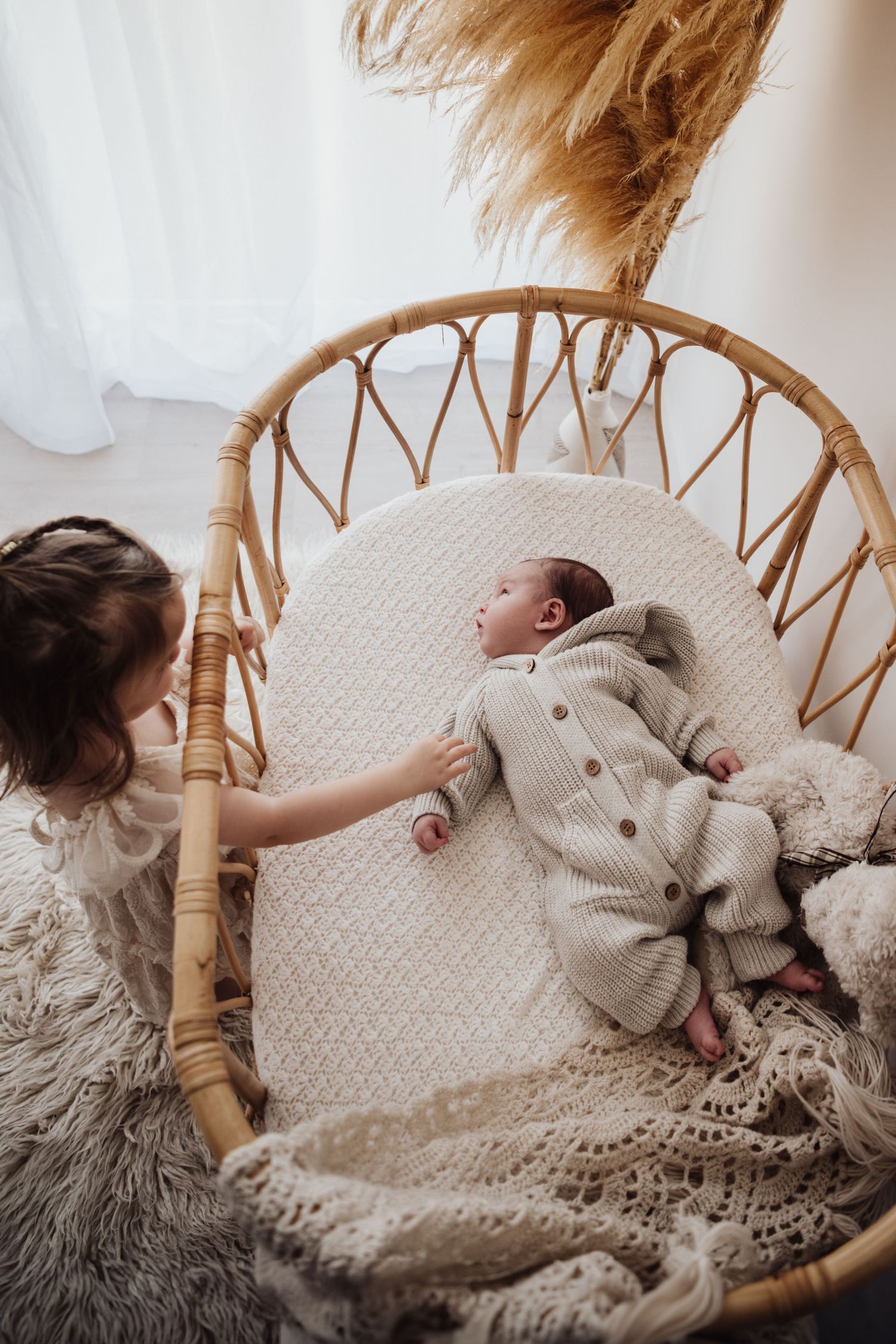 A sweet nursery scene with a baby resting in a rattan chair with plush decorations.
