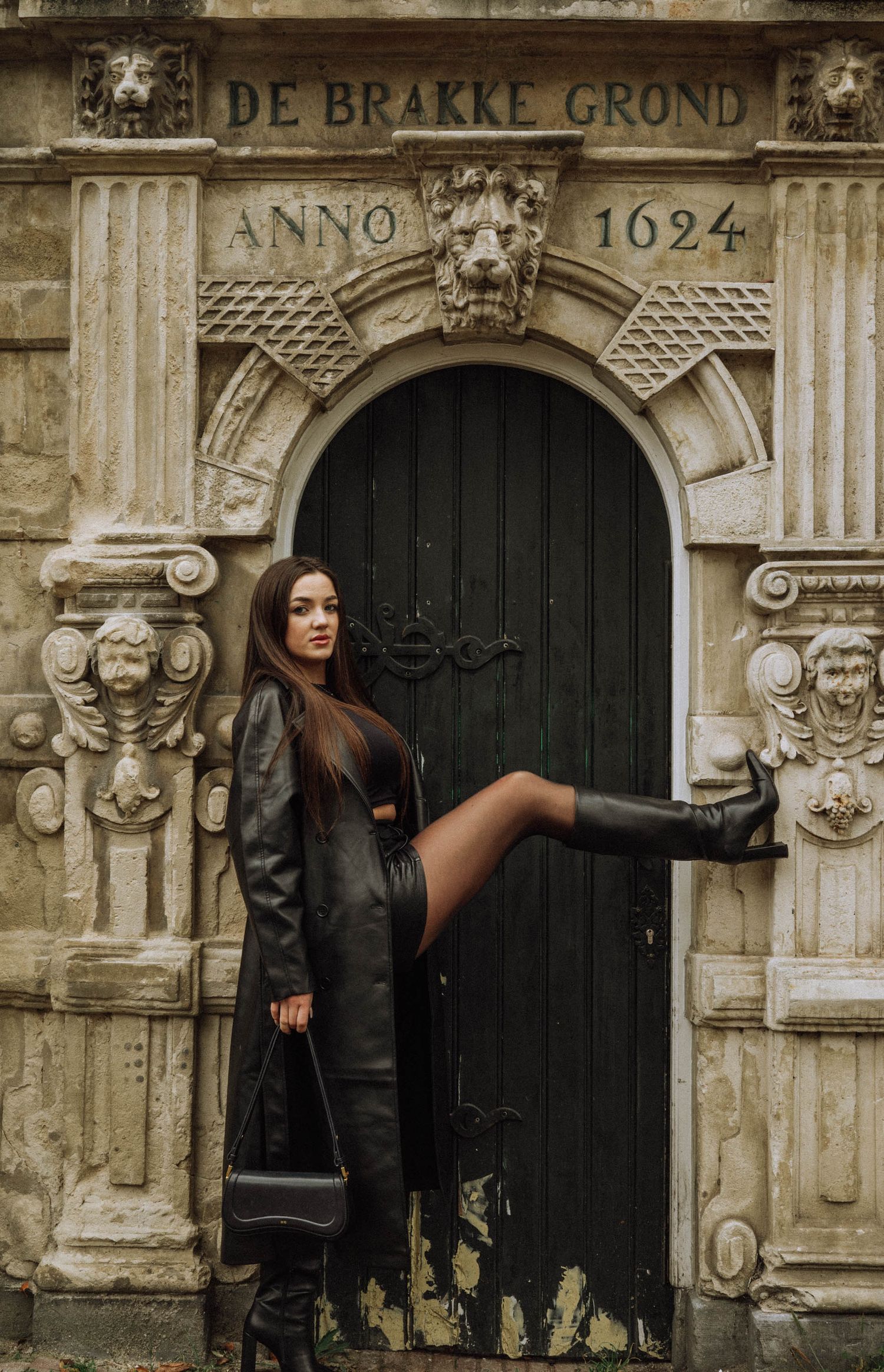 Individual portrait of a woman in a black leather coat in the historic district of Amsterdam.