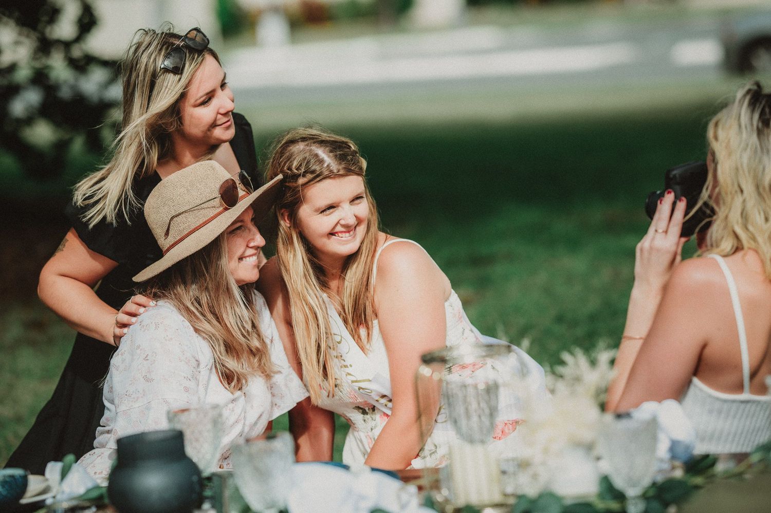 Friends in bohemian attire gather for outdoor picnic celebration.