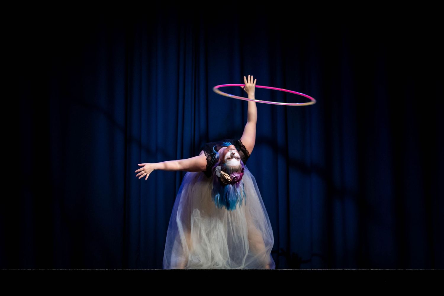 event photography Brighton of a Circus performer using a hoop onstage she wears a net skirt and halloween make up