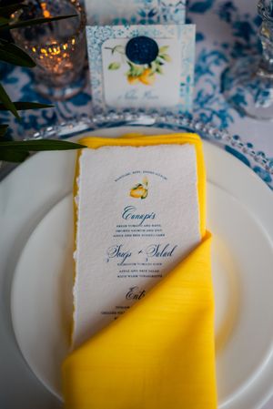 Multiple images of elegant wedding invitation cards with yellow accents and blue text arranged on white plates.